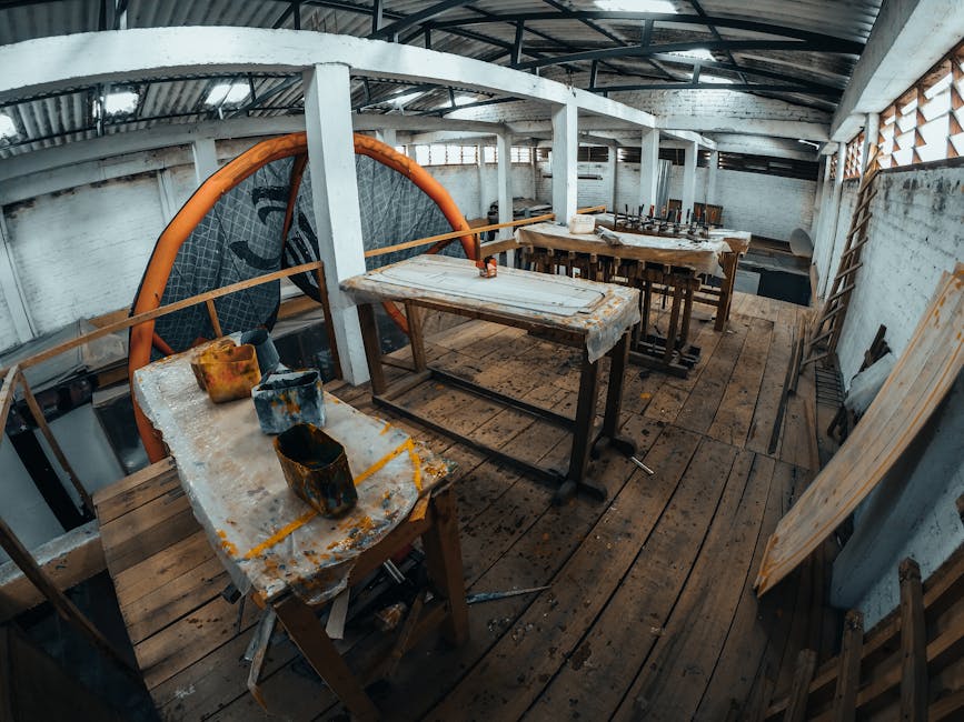 A rustic indoor workshop with wooden tables, paint cans, and industrial decor.